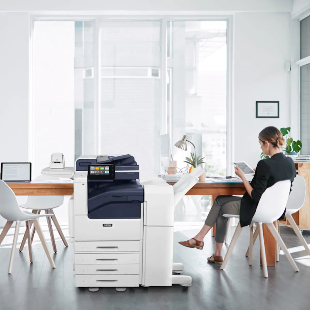 Kobieta siedząca obok urządzenia wielofunkcyjnego Xerox